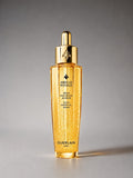 Flacon doré du sérum Abeille Royale de Guerlain, texture huile en eau avec bulles, bouchon doré orné d'une abeille.